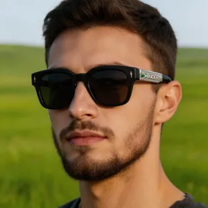 Detail of black square sunglasses with silver embossed temples and a green gemstone inlay