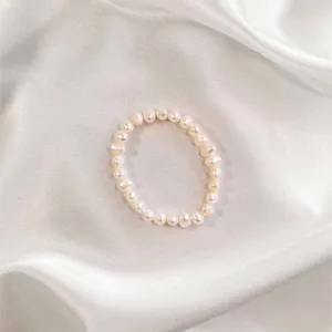 Detailed view of white freshwater baroque pearl ring on elegant white silk background