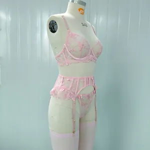 Dettaglio ricamo floreale rosa e balze in pizzo su un set di lingerie con calze rosa