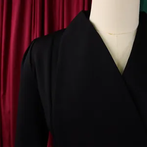 Détail de combinaison noire élégante montrant le col en V et les plis aux épaules
