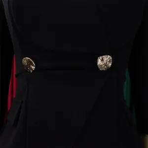 Détail de boutons dorés texturés sur une combinaison noire ajustée avec revers de poches