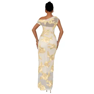 Detail of elegant white mesh evening dress with gold floral embroidery and one-shoulder cut