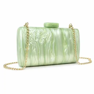 Detail of light green acrylic evening bag with marble texture and gold chain strap