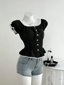 Dettaglio top nero attillato con bordo in pizzo bianco e bottoni floreali su manichino