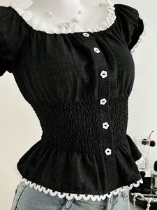 Dettaglio top nero con pizzo bianco, bottoni a fiore e vita elasticizzata arricciata