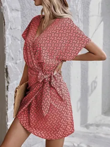 Détail de robe cache-cœur rose à col en V avec nœud à la taille et motif de chaînes