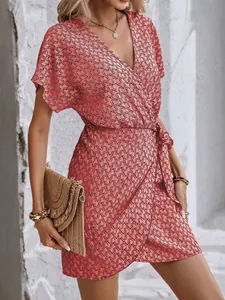 Détail d'une robe cache-cœur rose à fleurs avec taille ceinturée et col en V à manches courtes