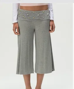 Detail of high-waist grey culottes featuring decorative metal studs on the waistband