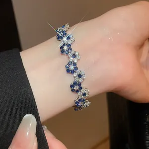 Detail view of a sparkly flower bracelet with blue and white gemstones on a wrist.