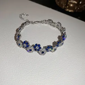 Detailed close-up shot of sparkling blue and white flower bracelet on textured white surface