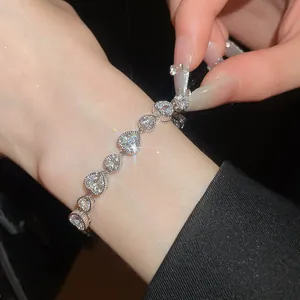 Detailed view of a sparkling silver bracelet with heart-shaped crystals on a wrist.