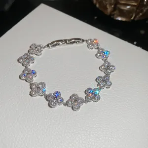 Detailed close-up of a silver four-leaf clover bracelet with sparkling clear stones.
