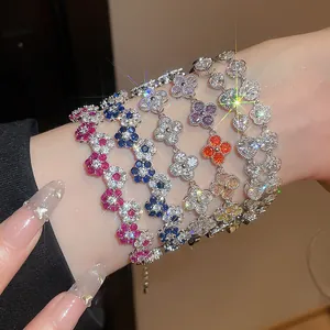 Detail showing five colorful sparkling flower bracelets on wrist with manicured nails