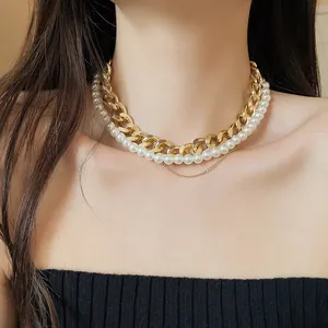 Detailed view of a multi-layer vintage gold curb chain and pearl choker necklace on a model