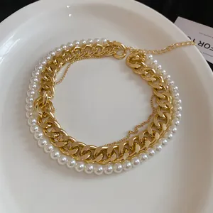 Close-up detail of the vintage gold Cuban chain and elegant white pearl layered necklace