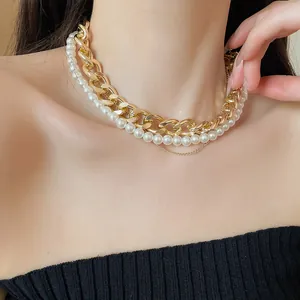 Detailed close-up showing a layered gold curb chain and pearl necklace on a model's neck