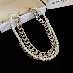 Macro view of detailed layered silver-tone curb chain and elegant white pearl necklace