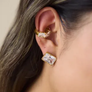 Close-up detail of sparkling rectangular zircon earrings and ear cuff set in gold finish