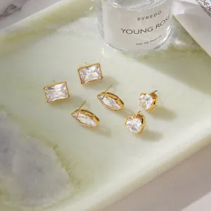 Close-up of sparkling heart, oval, and rectangular zircon stud earrings in gold finish