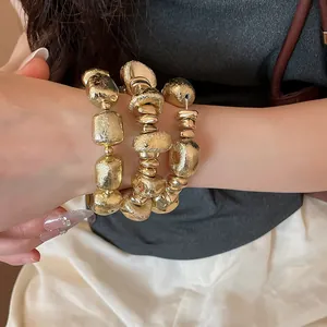 Primo piano di un set di bracciali a perline dorate geometriche irregolari sul polso