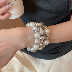 Primo piano di eleganti bracciali di perle con perle bianche e sfere d'argento martellate
