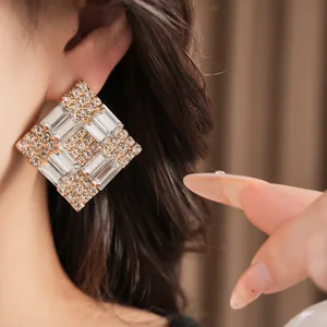 Close-up of geometric square earrings with sparkling clear crystals and gold plating
