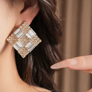 Close-up view of elegant sparkling rhinestone rhombus earrings worn on a female ear