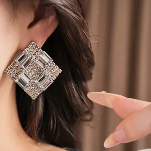 Detailed macro view of elegant square rhinestone stud earrings shown on an Asian model