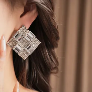 Macro detail of a sparkling square rhinestone stud earring worn by a female model