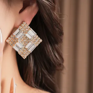 Close-up of luxury square stud earrings with clear sparkling crystals on gold setting
