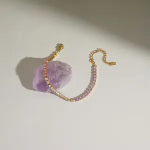 Dettaglio di un bracciale in acciaio inossidabile dorato con zirconi lavanda e chiari.