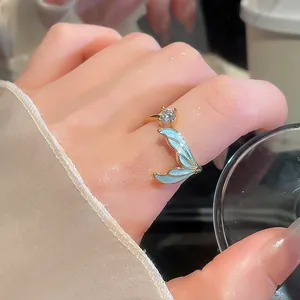 Gedetailleerd beeld van de sprankelende zirkoon en elegante blauwe emaille zeemeerminstaart ring.