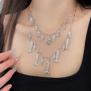 Primer plano de collar vintage de doble capa con pequeños colgantes de peces plateados.