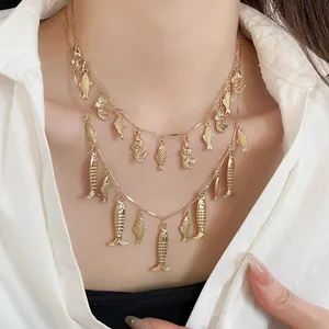 Vista detallada de un collar vintage dorado de dos capas con pequeños colgantes de peces