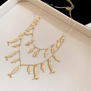 Primer plano de un collar dorado de dos capas con dijes de peces detallados.