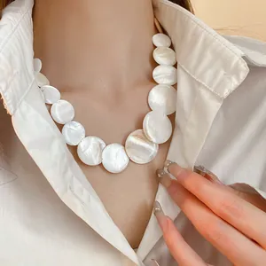 Detailed view of the round white shell geometric choker necklace on model.