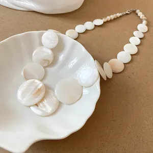 Detail view of iridescent round shell pieces on a geometric vacation style necklace