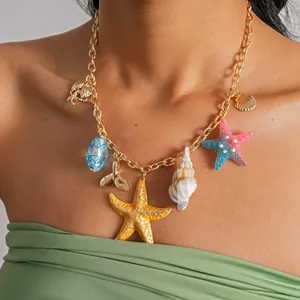 Détail d'un collier chaîne dorée avec des breloques étoiles de mer et coquillages en résine.