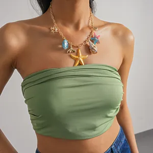 Détail de pendentifs étoile de mer et coquillage en résine sur un collier doré porté