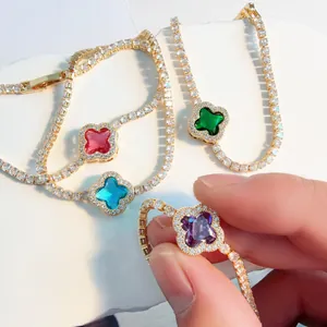 Close-up detail of elegant gold-plated four-leaf clover bracelets with colorful crystals