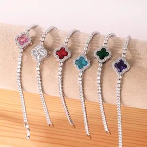 Close-up of elegant four-leaf clover bracelets with multi-colored crystals on a stand.