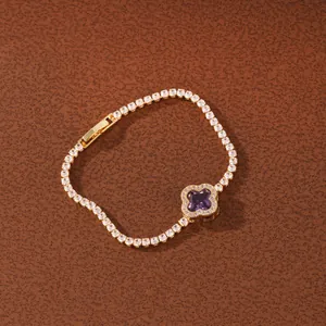 Close-up of elegant gold-plated tennis bracelet with purple clover and white zircons