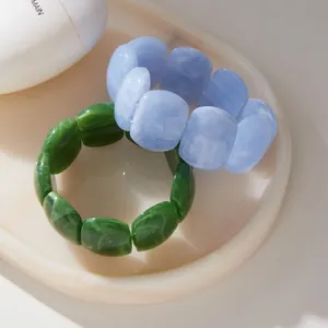 Close-up of marble pattern blue and green wide acrylic resin bracelets on stone plate
