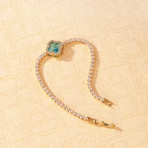 Close-up of gold plated bracelet featuring a blue four-leaf clover crystal pendant
