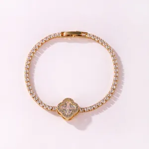 Close-up view of a gold-plated tennis bracelet featuring a sparkling four-leaf clover motif