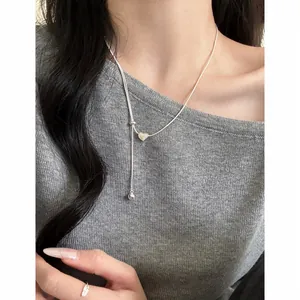Dettaglio raffinato di una collana a cuore argento minimalista regolabile sul collo.