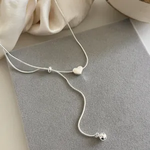 Primo piano di collana a cuore in argento minimalista con design a catena scorrevole.