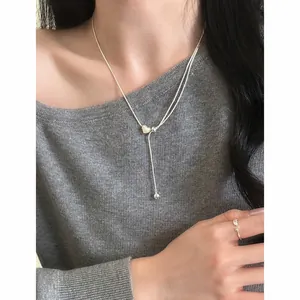 Primo piano di una collana a Y in argento con cuore regolabile su una modella
