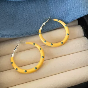 Detailed macro view of yellow oil-dripped polka dot hoop earrings on a velvet jewelry tray