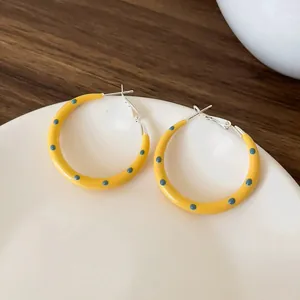 Vibrant yellow enamel hoop earrings featuring blue polka dots and silver needles detail
